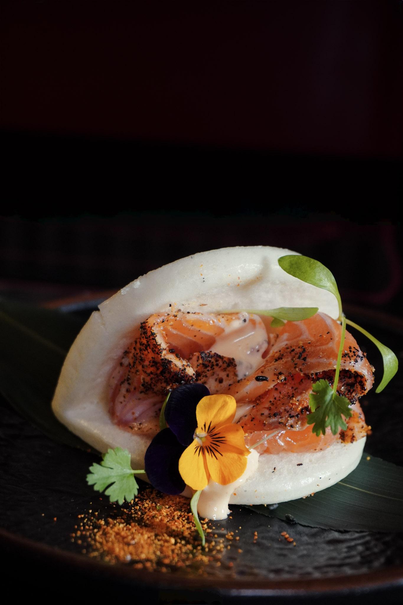 Salmon bao bun with edible flowers.
