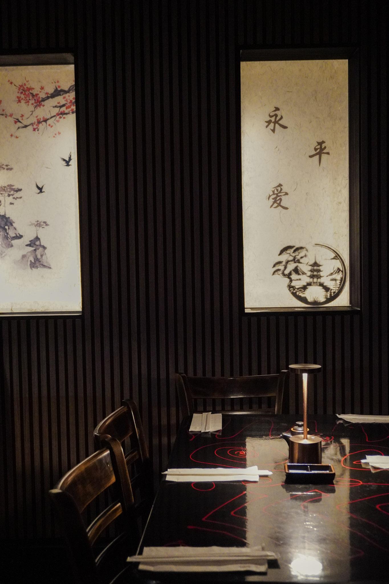 Moody Tokyo Sushi Speakeasy table setting with Japanese wall art.