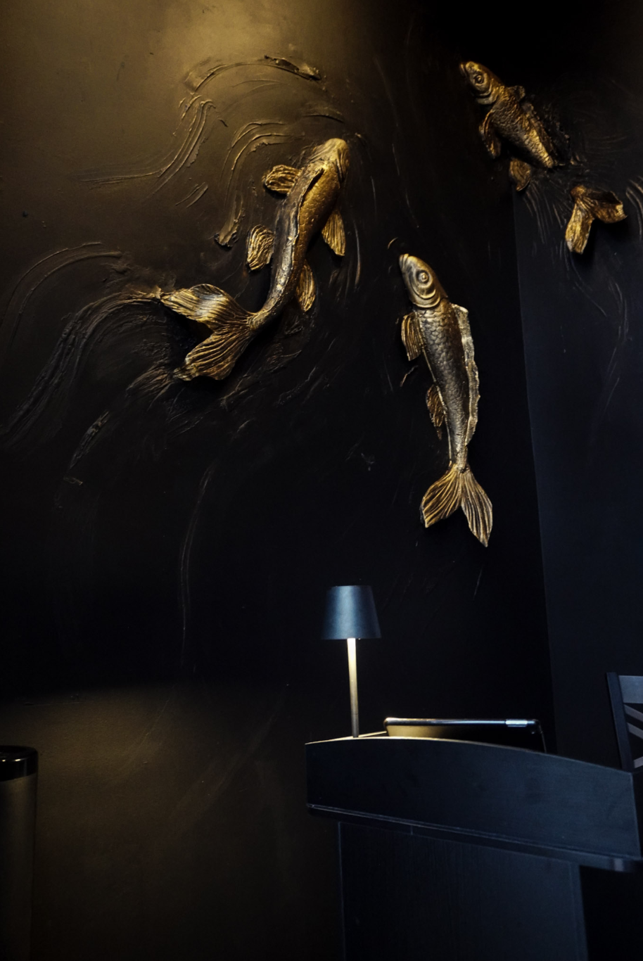 The intimate Tokyo Sushi Speakeasy dining room in warm, moody light.